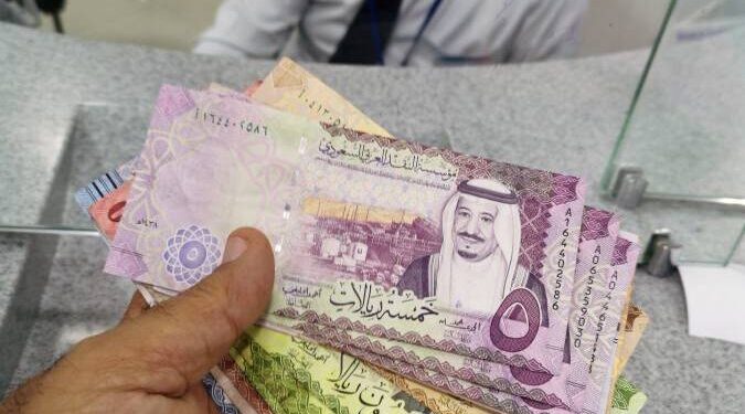 A man poses with Saudi currency, riyal at a local currency exchange in Manama, Bahrain October 16, 2018. REUTERS/ Hamad I Mohammed أسعار الريال السعودي اليوم الأربعاء