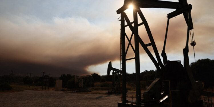 LOS OLIVOS, CALIFORNIA - JULY 06: Oil pumpjacks operate as the Lake Fire burns in Los Padres National Forest with evacuation warnings in the area on July 6, 2024 near Los Olivos, California. The wildfire in Santa Barbara County has scorched 4,600 acres amid a long-duration heat wave which is impacting much of California.   Mario Tama/Getty Images/AFP (Photo by MARIO TAMA / GETTY IMAGES NORTH AMERICA / Getty Images via AFP) النفط يتراجع وسط ترقب لقرار أوبك+ بشأن الإمدادات