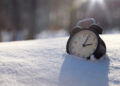 Closeup image of alarm clock in snow. Spring time concept image with copyspace رسمياً.. بدء تطبيق التوقيت الشتوي في مصر