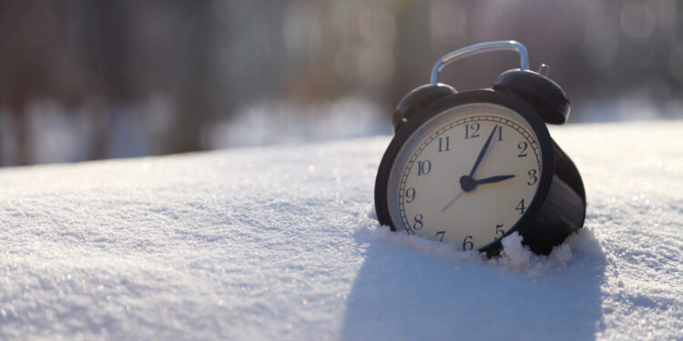 Closeup image of alarm clock in snow. Spring time concept image with copyspace رسمياً.. بدء تطبيق التوقيت الشتوي في مصر